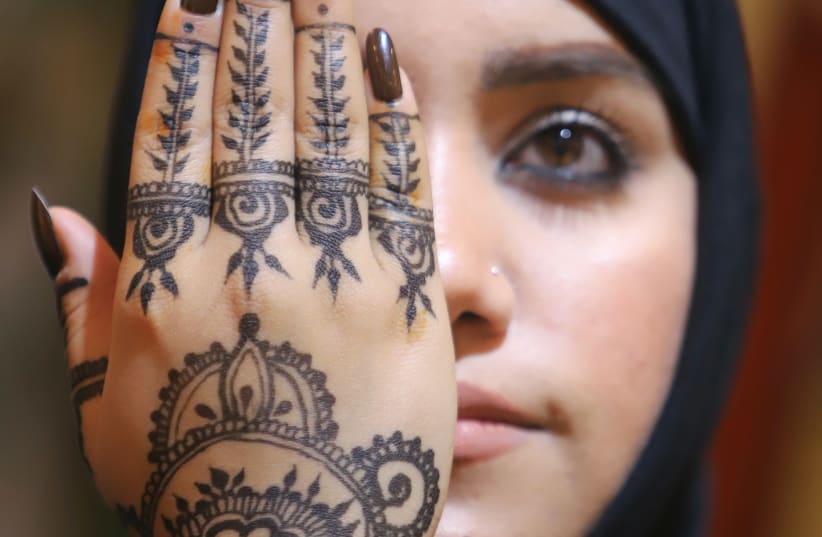 An Iraqi woman holds up her hand decorated with henna inside her beauty shop in Basra (photo credit: ESSAM AL-SUDANI/ REUTERS)
