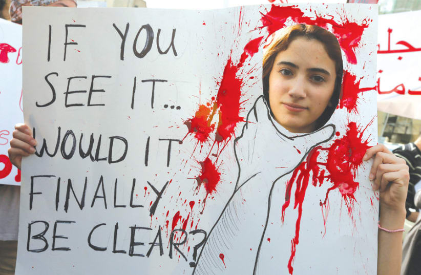 AN ACTIVIST holds a banner during a march protesting domestic violence against women, in Beirut on March 8, 2014, International Women’s Day. (photo credit: JAMAL SAIDI/ REUTERS)