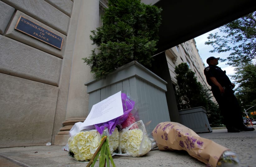 A police officer stands guard near a makeshift memorial at the Consulate General of France in Manhattan following the Nice terror attack in New York, U.S., July 15, 2016 (photo credit: ANDREW KELLY / REUTERS)