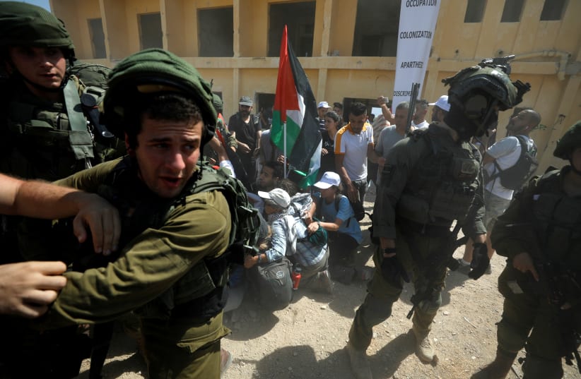 Israeli soldiers detain local and foreign activists during a protest against Jewish settlements, near the Dead Sea in the Megilot Region of the West Bank. September 28, 2019.  (photo credit: REUTERS/MOHAMAD TOROKMAN)