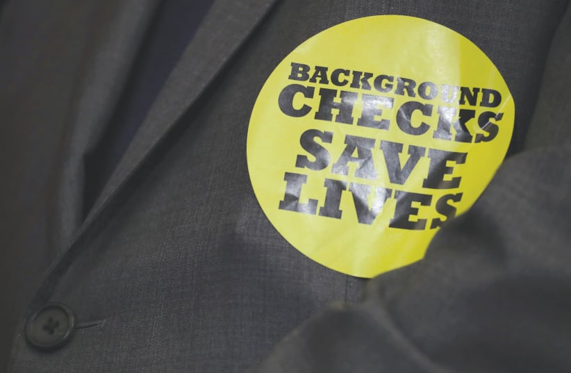 A MEMBER of Congress wears a sticker during a news conference announcing the introduction of bipartisan legislation to expand background checks for sales and transfers of firearms in January.  (photo credit: REUTERS / JONATHAN ERNST)