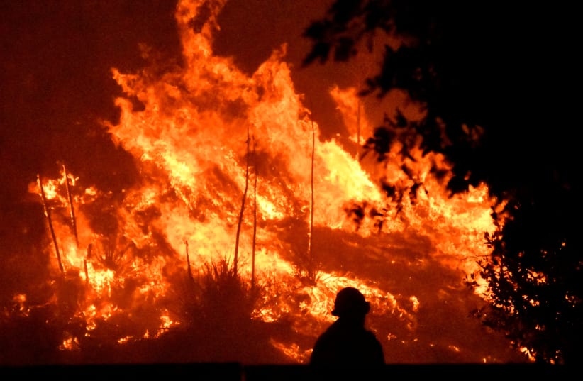 Firefighters battle a wind-driven wildfire called the Saddle Ridge fire in the early morning hours Friday in Porter Ranch, California, U.S., October 11, 2019. (photo credit: GENE BLEVINS / REUTERS)