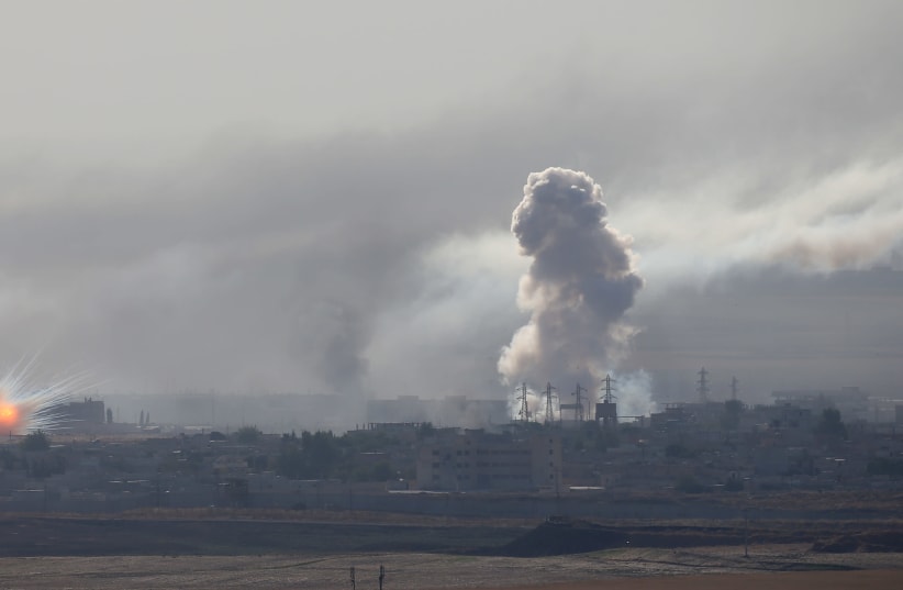 An explosion and smoke are seen over the Syrian town of Ras al-Ain as seen from the Turkish border town of Ceylanpinar, Sanliurfa province, Turkey, October 12, 2019 (photo credit: REUTERS/STOYAN NENOV)