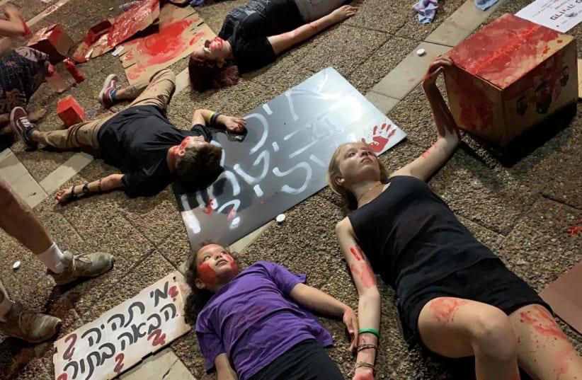 Children lie on the ground, covered in red paint, as part of a Women's Rally in Tel Aviv to protest the government's inaction on the issue of violence against women. (photo credit: Courtesy)