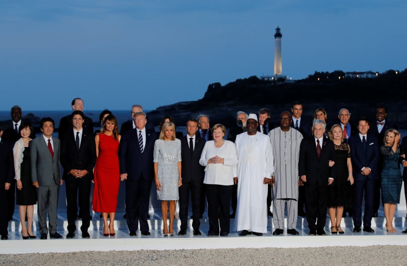 French President Emmanuel Macron, U.S. President Donald Trump, Japan's Prime Minister Shinzo Abe, German Chancellor Angela Merkel, Canada's Prime Minister Justin Trudeau and Italy's acting Prime Minister Giuseppe Conte pose for a family photo with invited guests during the G7 summit in Biarritz, Fra (photo credit: REUTERS/PHILIPPE WOJAZER)