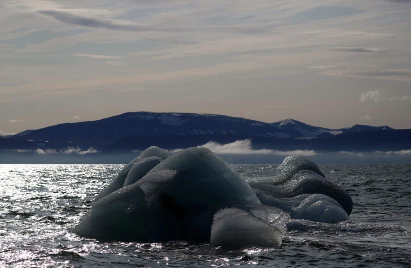 An iceberg floats near the Wahlenberg Glacier in Oscar II land at Spitsbergen in Svalbard, Norway, August 5, 2019. (photo credit: REUTERS / HANNAH MCKAY)