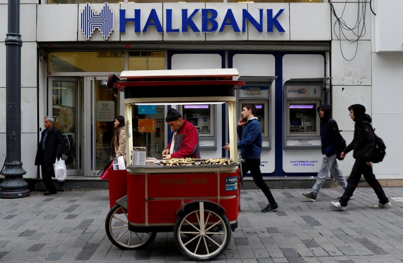 FILE PHOTO: A street vendor sells roasted chestnuts in front of a branch of Halkbank in central Istanbul, Turkey, January 10, 2018 (photo credit: REUTERS/MURAD SEZER/FILE PHOTO)