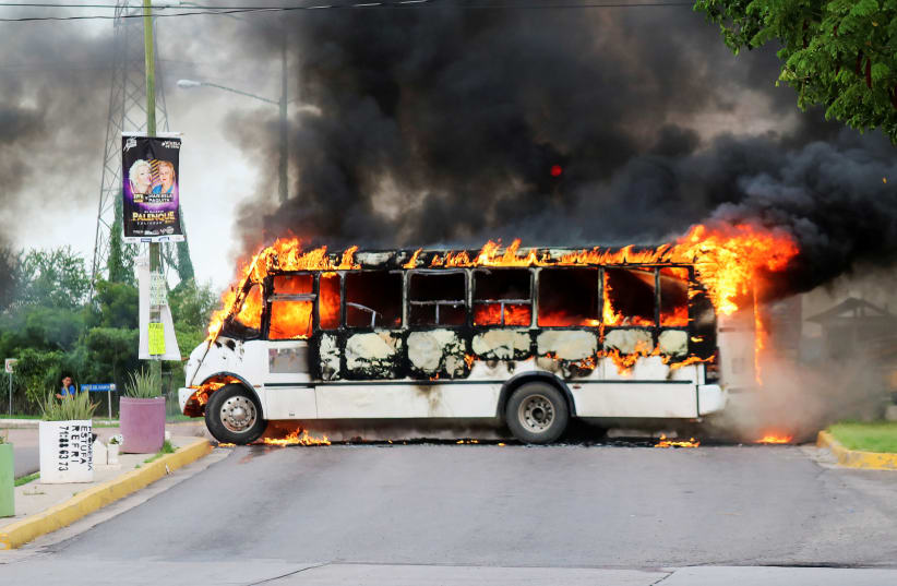 A burning bus, set alight by cartel gunmen to block a road, is pictured during clashes with federal forces following the detention of Ovidio Guzman, son of drug kingpin Joaquin "El Chapo" Guzman, in Culiacan, Sinaloa state, Mexico October 17, 2019 (photo credit: REUTERS/JESUS BUSTAMANTE)