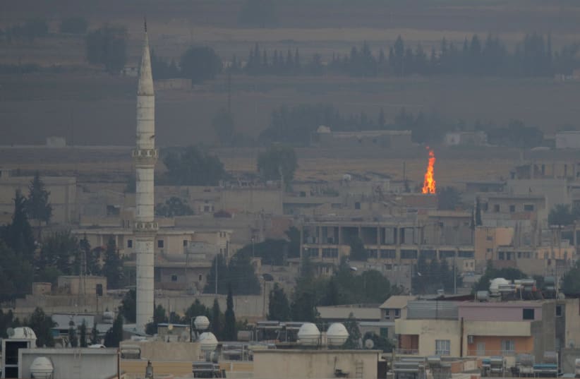 A fire is seen in the Syrian town of Ras al-Ain as seen from the Turkish border town of Ceylanpinar, Sanliurfa province, Turkey, October 17, 2019 (photo credit: REUTERS/STOYAN NENOV)