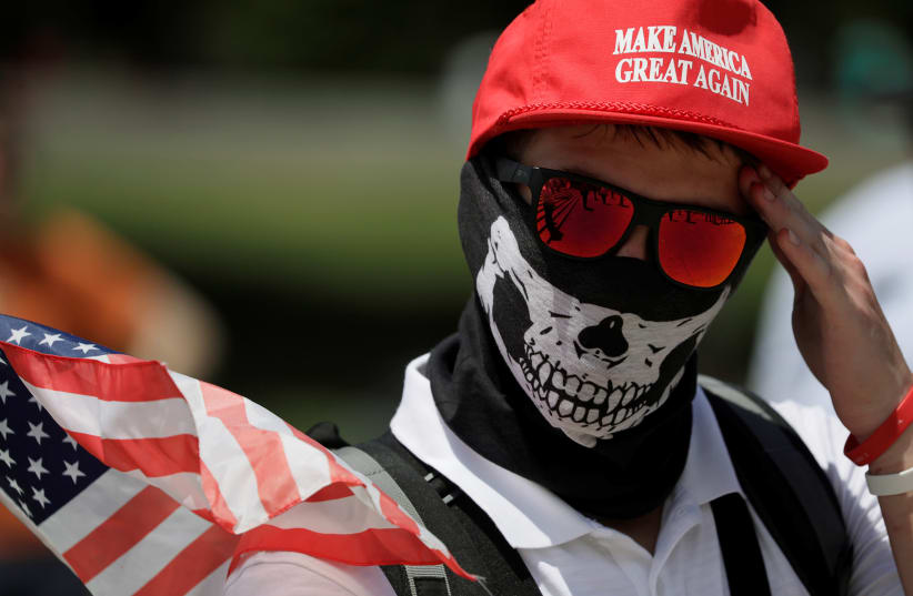 A masked demonstrator in a Donald Trump "Make America Great Again" hat wipes his brow as self proclaimed "White Nationalists", white supremacists and members of the "Alt-Right" gather for what they called a "Freedom of Speech" rally at the Lincoln Memorial in Washington, U.S. June 25, 2017 (photo credit: JIM BOURG / REUTERS)