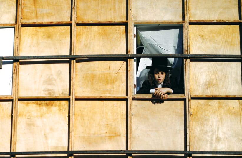 A BOY looks out through a window of a sukkah in Ashdod (photo credit: AMIR COHEN/REUTERS)
