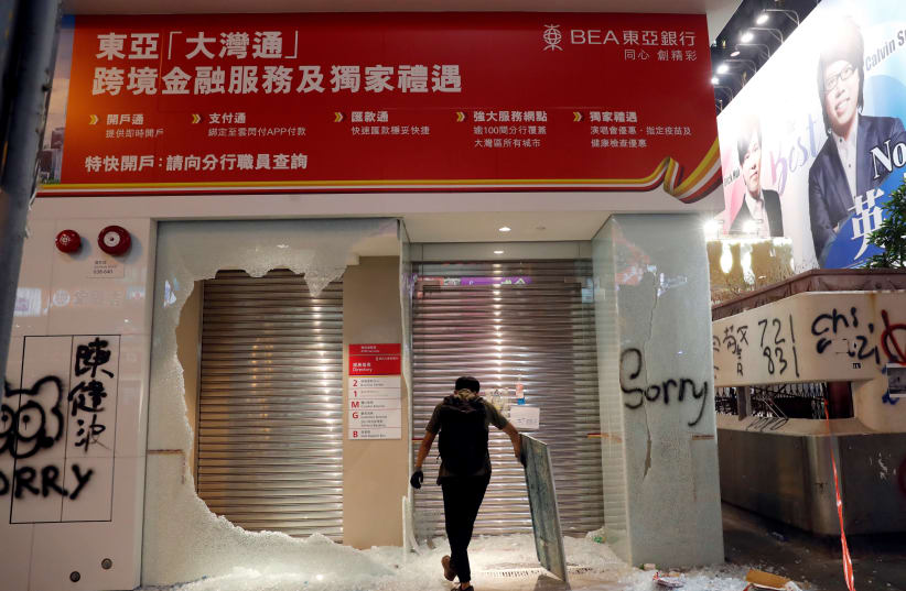 A man stands in front of the Bank of East Asia (BEA) that was vandalised by anti-government protesters in Hong Kong, China, October 20, 2019 (photo credit: REUTERS/KIM KYUNG-HOON)