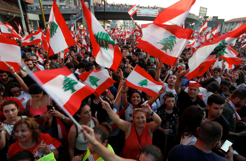 Demonstrators carry national flags and gesture during an anti-government protest along a highway in Jal el-Dib, Lebanon October 21, 2019 (photo credit: REUTERS/MOHAMED AZAKIR)