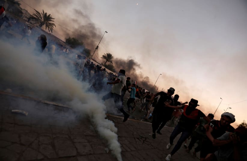 Demonstrators disperse as Iraqi security forces use tear gas during a protest after the lifting of the curfew, following four days of nationwide anti-government protests that turned violent, in Baghdad (photo credit: REUTERS)