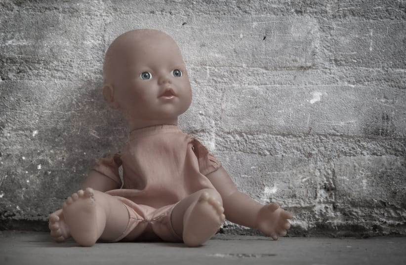 Abandoned doll sitting on a concrete floor (photo credit: INGIMAGE)