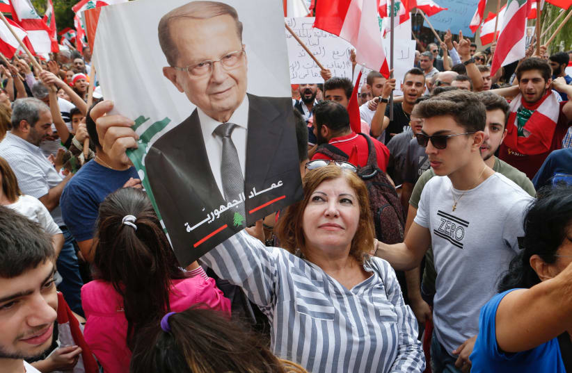 Supporters of Lebanese President Michel Aoun carry his picture near the presidential palace in Baabda, ahead of his address to the nation (photo credit: REUTERS/MOHAMED AZAKIR)