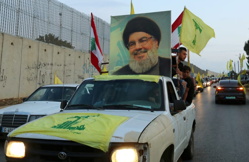 Supporters of Lebanon's Hezbollah leader Sayyed Hassan Nasrallah ride in a vehicle decorated with Hezbollah and Lebanese flags and a picture of him, as part of a convoy in the southern village of Kfar Kila, Lebanon October 25, 2019 (photo credit: AZIZ TAHER/REUTERS)