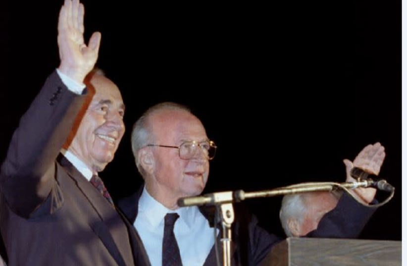 Prime Minister Yitzhak Rabin (right) and Foreign Minister Shimon Peres wave to a huge crowd at the peace rally on November 4, 1995. (photo credit: HAVAKUK LEVISON / REUTERS)