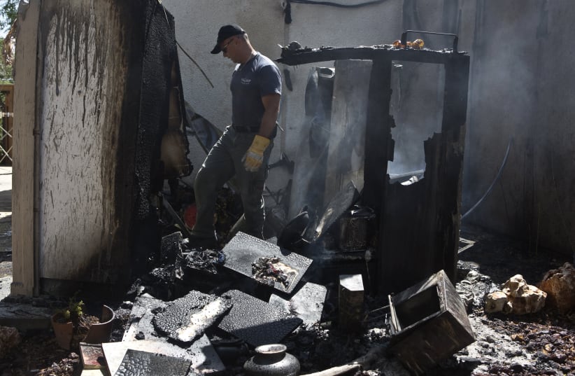 AN ISRAELI police explosives expert surveys the damage after a rocket from Gaza exploded in an Israeli community south of Ashkelon. July 14, 2014.   (photo credit: NIR ELIAS / REUTERS)