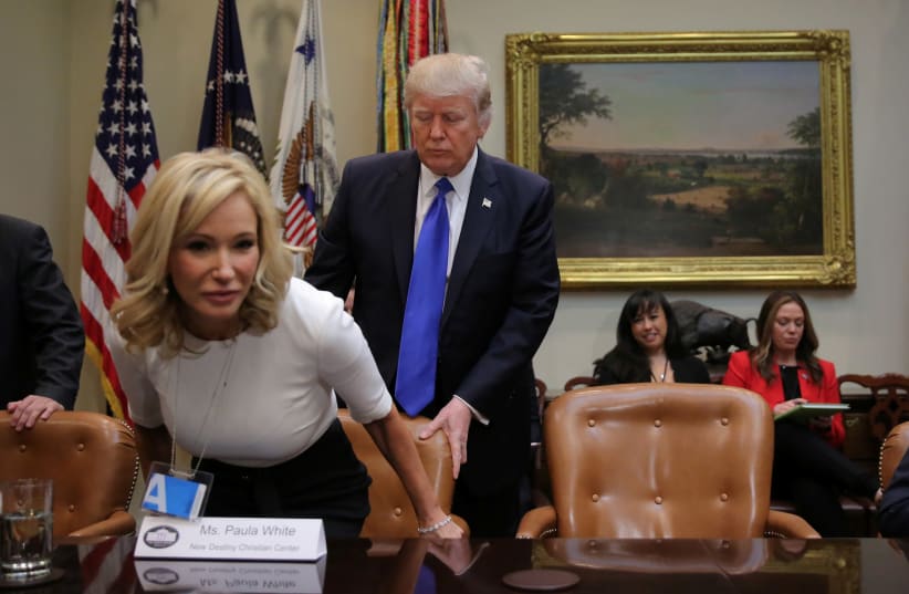 U.S. President Donald Trump pulls a chair out for Paula White from the New Christian Destiny Center to as they attend a meeting regarding the supreme court nomination at the Roosevelt room of the White House in Washington, U.S., February 1, 2017 (photo credit: CARLOS BARRIA / REUTERS)