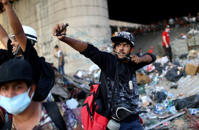 An Iraqi demonstrator uses a sling shot during the ongoing anti-government protests in Baghdad (photo credit: REUTERS)