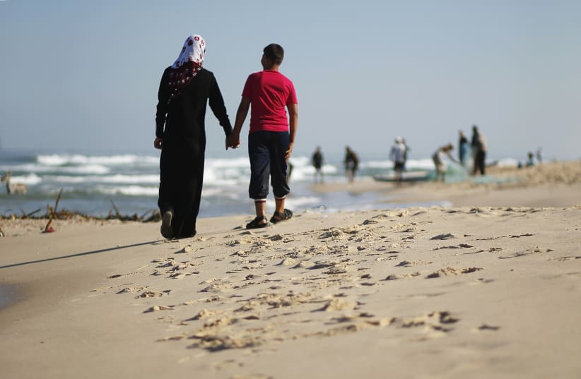 Newly married Tala Soboh, 14, and her 15-year-old husband Ahmed walk on the beach two days after their marriage in the town of Beit Lahiya, in the northern Gaza Strip September 26, 2013. The newlyweds live in the family's three-room home, sharing it with nine relatives. Ahmed works with his father a (photo credit: REUTERS)