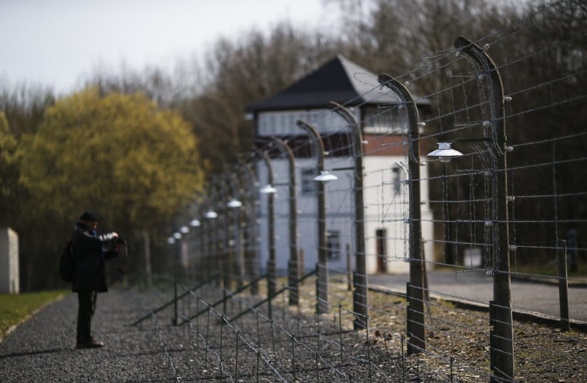 A visitor stands in front of a watchtower behind a fence on the grounds of the former Nazi concentration camp Buchenwald near Weimar (photo credit: REUTERS)