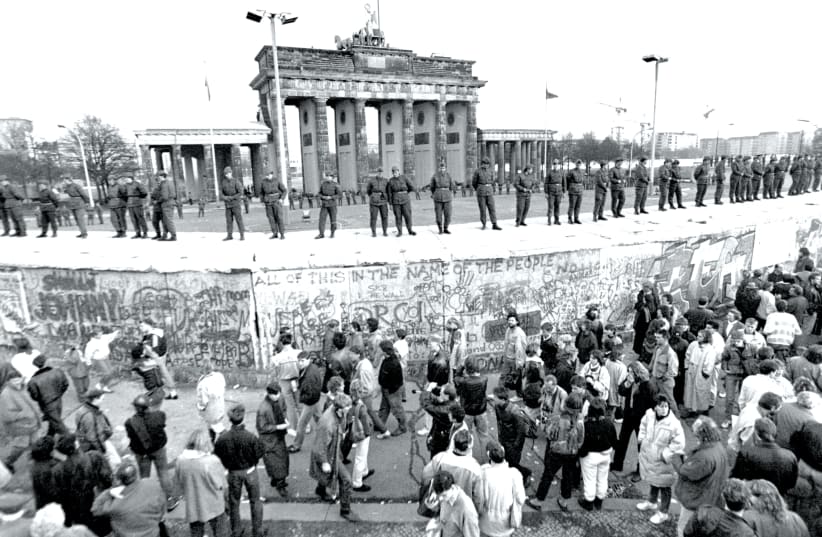 SOLDIERS STAND at ease on top of the Berlin Wall, in front of Brandenburg Gate, on November 10, 1989 (photo credit: ANDREW STAWICKI/TORONTO STAR/ZUMA PRESS/TNS)