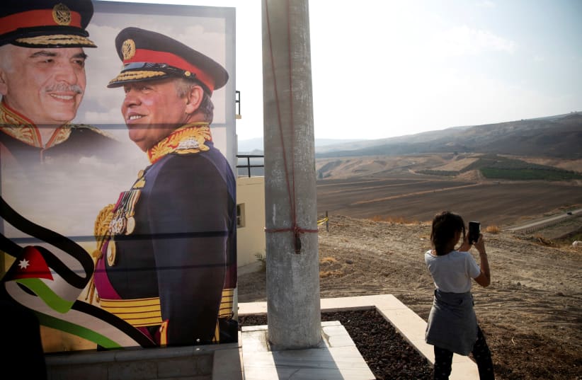 A picture of Jordanian King Abdullah and his father, the late King Hussein, is seen as a girl visits the "Island of Peace" in an area known asNaharayim in Hebrew and Baquora in Arabic, on the Jordanian side of the border with Israel November 9, 2019 (photo credit: REUTERS)