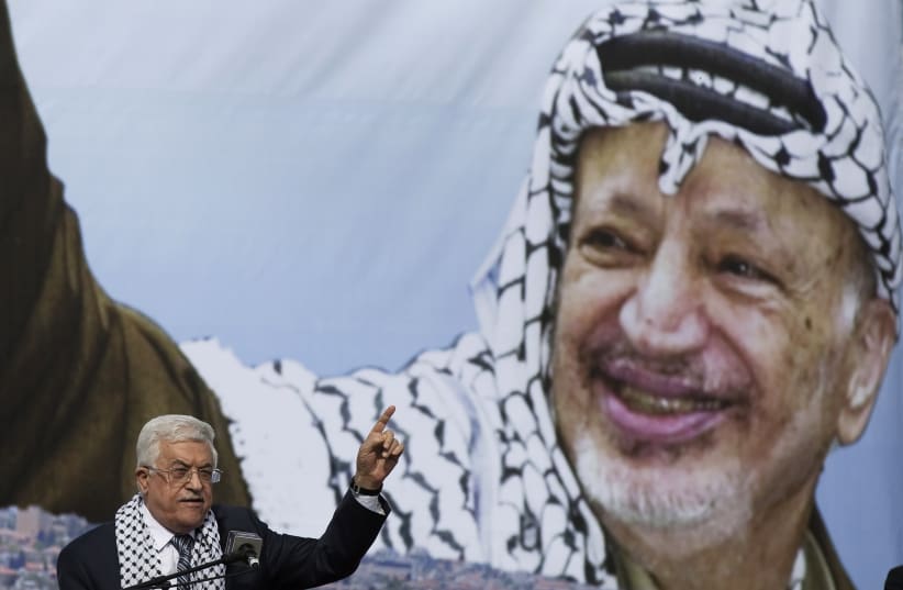 Palestinian President Mahmoud Abbas gestures beneath a poster of the late Palestinian leader Yasser Arafat (photo credit: FINBARR O'REILLY / REUTERS)