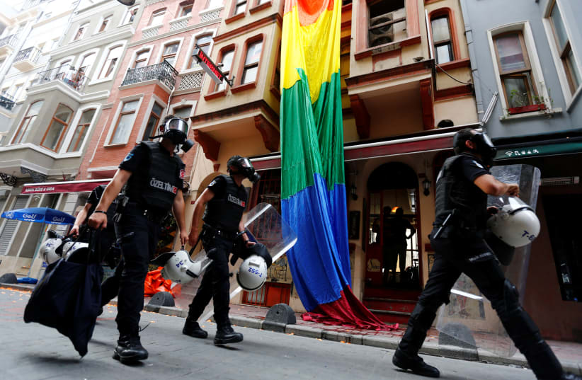 Riot police, with a rainbow flag in the background, chase LGBT rights activists as they try to gather for a pride parade in Istanbul, Turkey (photo credit: MURAD SEZER/REUTERS)