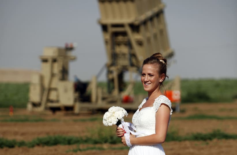 Israeli bride Shiklar poses for a wedding photo in front of an Iron Dome rocket launcher near Netivot (photo credit: REUTERS/AMIR COHEN)