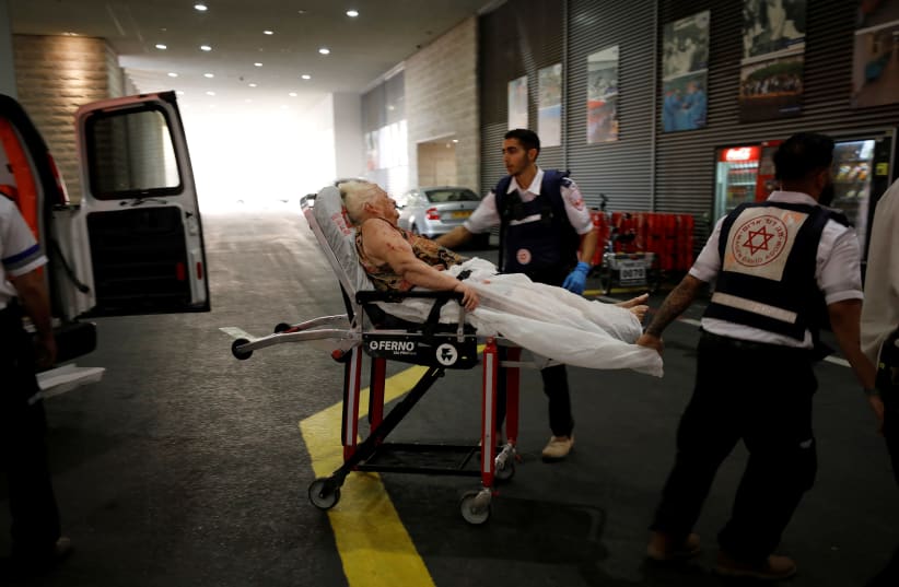 An injured woman is evacuated to hospital after a rocket was fired from Gaza into Israel, in Ashkelon, southern Israel (photo credit: REUTERS/AMIR COHEN)