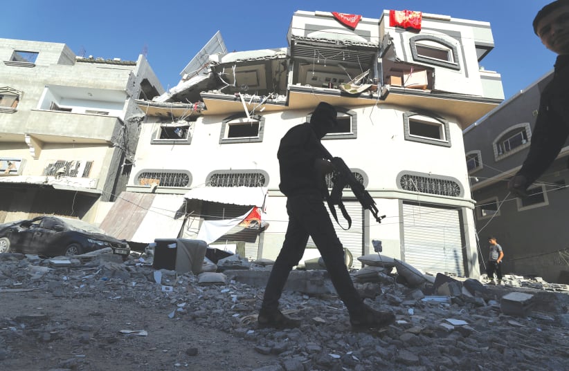 AN ARMED man walks past the home of Islamic Jihad commander Bahaa Abu al-Ata after it was bombed on Tuesday.  (photo credit: MOHAMMED SALEM/ REUTERS)