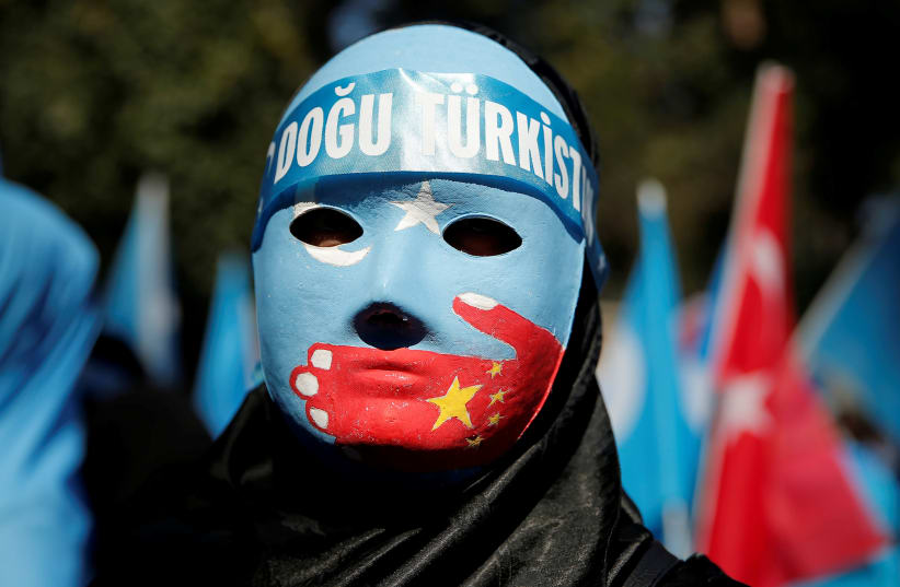 An ethnic Uighur demonstrator wears a mask as she attends a protest against China in front of the Chinese Consulate in Istanbul (photo credit: HUSEYIN ALDEMIR/REUTERS)