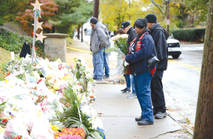 People gather at makeshift memorial a block from the scene the shooting last year of the Tree of Life Synagogue in Pittsburgh Pennsylvania.   (photo credit: ALAN FREED/REUTERS)