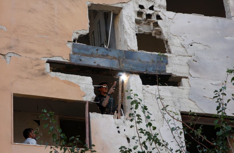 A worker fixes the damage to a building from an Israeli attack in Damascus, Syria November 20, 2019. (photo credit: REUTERS/OMAR SANADIKI)