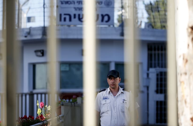 An Israeli prison guard is seen through a gate at Maasiyahu prison near Ramle, south of Tel Aviv, Israel February 15, 2016. Former Israeli Prime Minister Olmert begins his 19-month prison sentence at Maasiyahu prison on Monday, making him the first former head of government in Israel to go to prison (photo credit: BAZ RATNER/REUTERS)