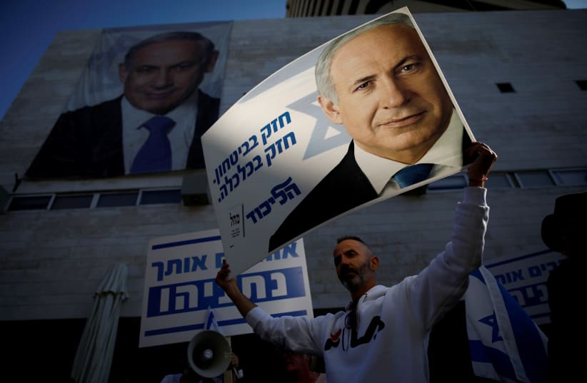 Supporters of Israeli Prime Minister Benjamin Netanyahu protest outside Likud Party headquarters in Tel Aviv, Israel November 22, 2019. The placards in Hebrew read, "Strong in security, strong in Economy " (photo credit: CORINNA KERN/REUTERS)
