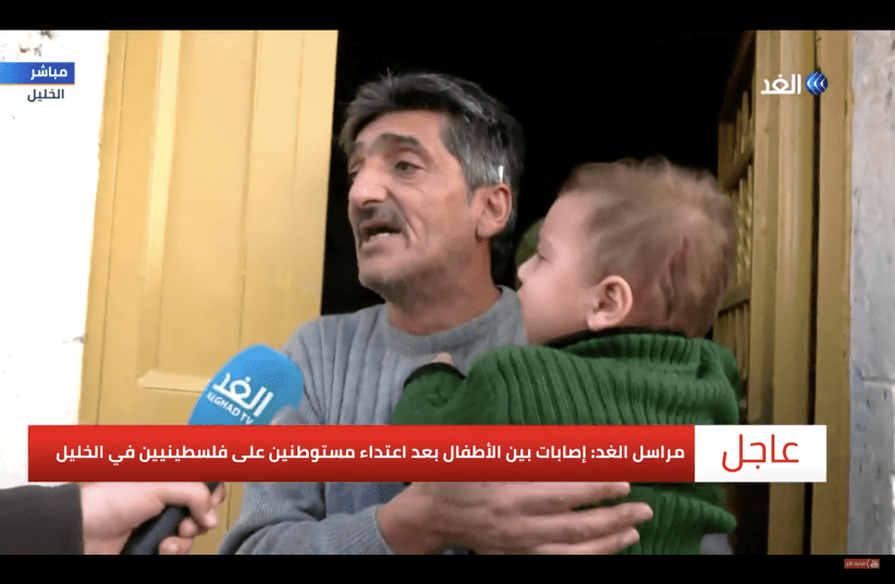 Emad Abu Shamsiyeh holds his injured grandson in his arms as he speaks with Al Ghad television about Saturday's attack. (photo credit: AL GHAD)