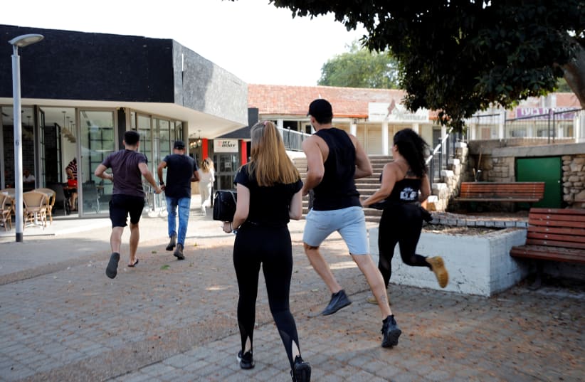 People run to take shelter as a siren warning of incoming rockets sounds in Ashkelon  on November 13 (photo credit: REUTERS)