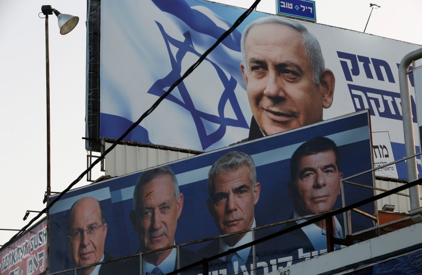 A Likud party election campaign billboard depicting Israeli Prime Minister Benjamin Netanyahu is seen above a billboard depicting Benny Gantz, leader of Blue and White party, in Petah Tikva, Israel (photo credit: NIR ELIAS / REUTERS)