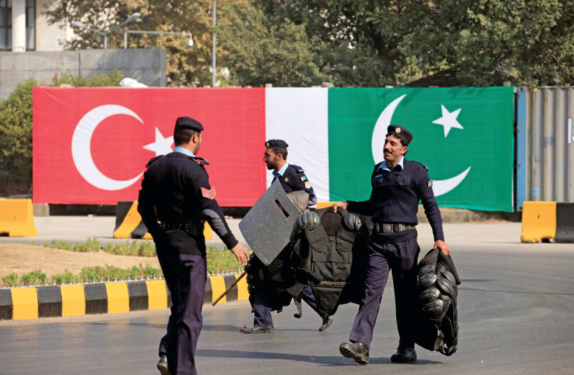 POLICEMEN WALK near the national flags of Pakistan and Turkey displayed along a road ahead of a visit of Turkish President Recep Tayyip Erdogan in Islamabad in 2016.  (photo credit: FAISAL MAHMOOD/REUTERS)