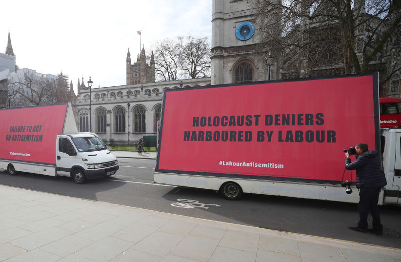 Vans with slogans aimed at Britain's Labour Party are driven around Parliament Square ahead of a debate on antisemitism in Parliament, in London, April 17, 2018 (photo credit: HANNAH MCKAY/ REUTERS)