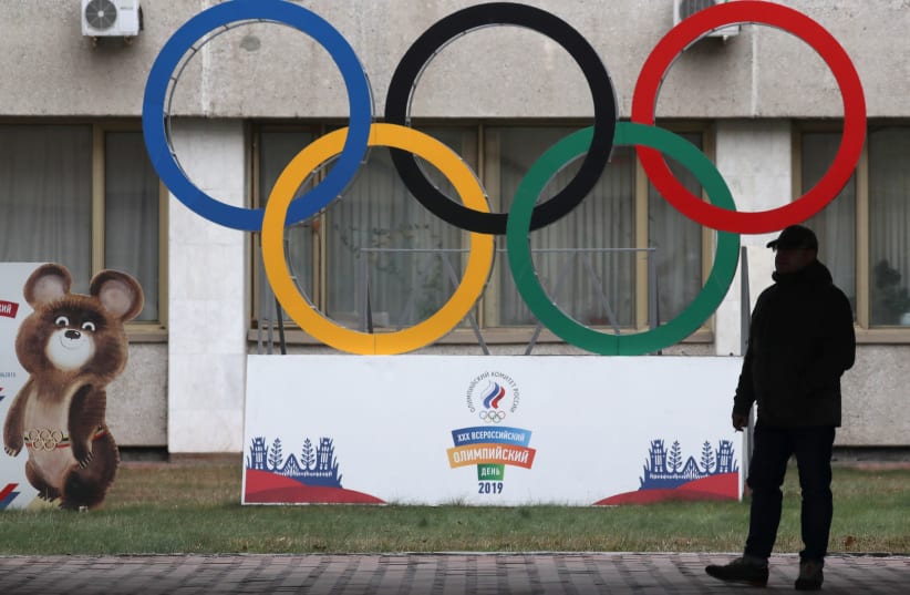 A man stands in front of the Olympic rings outside the headquarters of the Olympic Committee of Russia in Moscow, Russia November 28, 2019 (photo credit: REUTERS/EVGENIA NOVOZHENINA)