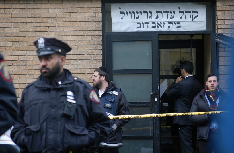 Hasidim, government officials and police officers stand in front of the K'hal Adas Greenville synagogue next door to JC Kosher Supermarket in Jersey City, N.J., the site of a deadly shooting, Dec. 11, 2019 (photo credit: LAURA E. ADKINS/JTA)
