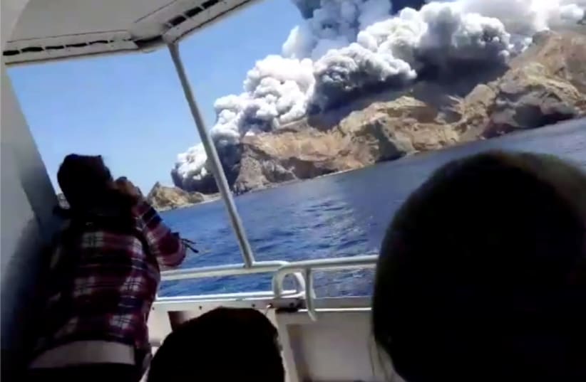 People on a boat react as smoke billows from the volcanic eruption of Whakaari, also known as White Island (photo credit: INSTAGRAM @ALLESSANDROKAUFFMANN/VIA REUTERS)