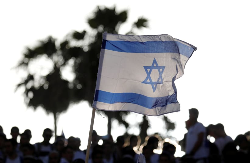 Jewish youth wave Israeli flags as they participate in a march marking "Jerusalem Day", near Damascus Gate in Jerusalem's Old City June 2, 2019 (photo credit: AMIR COHEN/REUTERS)