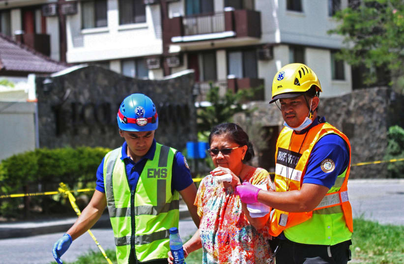Rescue workers assist a resident evacuating from a condominium building that sustained heavy damage after a 6.5 magnitude earthquake in Davao City, Mindanao, Philippines, October 31, 2019 (photo credit: REUTERS/LEAN DAVAL JR)