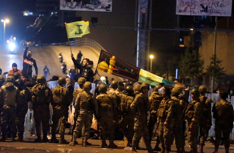 Supporters of the Lebanese Shi'ite groups Hezbollah and Amal carry flags as Lebanese army soldiers are deployed in Beirut, Lebanon amid protests (photo credit: REUTERS/MOHAMED AZAKIR)
